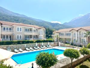a resort with a swimming pool and mountains in the background at Larimar Suite Hotel in Oludeniz