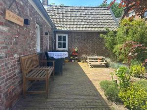 Helvoirt的住宿－Op den Distelberg，一个带长凳和砖砌建筑的庭院