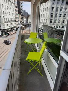 two green chairs and a table on a balcony at Lichtrijk en comfortabel hoekappartement met gratis parking en zeer centraal gelegen - Comme Chez Soi in Ostend