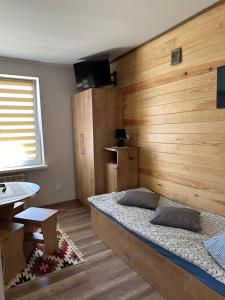 a bedroom with a bed with a wooden wall at Krok od Biebrzy in Dolistowo Stare