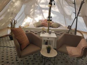 a room with two chairs and a bed in a tent at Sjugare Gård Glamping in Leksand