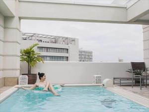 una mujer tendida en una piscina en un edificio en Okinawa EXES Naha en Naha
