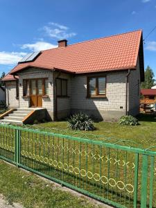 una casa con techo rojo y valla verde en Krok od Biebrzy en Stare Dolistowo