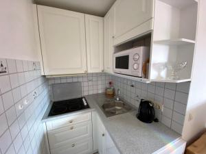 a kitchen with white cabinets and a sink and a microwave at Sylvie Steinhardt, Wohnung 3 in List