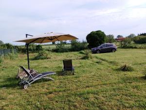 un parapluie et une chaise dans un champ avec une voiture dans l'établissement Casa Porciatti, à Grosseto