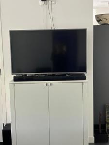 TV de pantalla plana en la parte superior de un armario blanco en B&B Kunstkamer Franeker, en Franeker