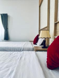 a bedroom with two beds with red pillows and a lamp at Miền Tây Hotel in Can Tho