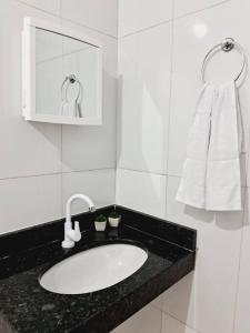 uma casa de banho branca com um lavatório e uma toalha em Flat aconchegante com entrada privativa proximo ao aeroporto e rodoviária em Palmas