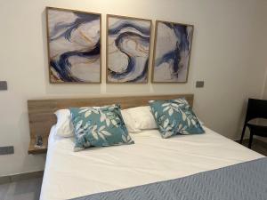 Villa Lucia في بومباي: غرفة نوم بسرير بثلاث لوحات على الحائط