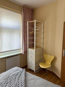 um quarto com um armário branco e uma cadeira amarela em Körner Nr 2 - ABC26 em Wismar