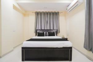 a bedroom with a black and white bed and a window at OYO Hotel Bluebird Inn in Nagpur