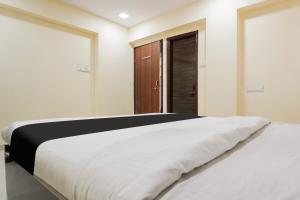 a bedroom with a large white bed and a wooden door at OYO Hotel Bluebird Inn in Nagpur