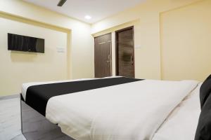 um quarto com uma cama branca e uma televisão em OYO Hotel Bluebird Inn em Nagpur