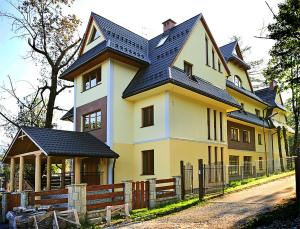 a large yellow house with a black roof at Apartament Cicha Woda Zakopane in Zakopane