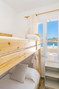 two bunk beds in a bedroom with a view of the beach at Ponent-Apartamento frente al mar, refugio costero in Es Grau