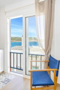 Ponent-Apartamento frente al mar, refugio costero في Es Grau: كرسي أزرق في غرفة مطلة على المحيط