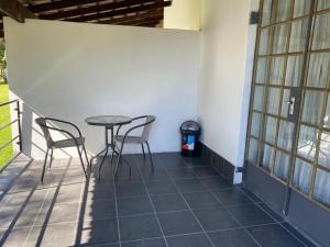 a patio with two chairs and a table and a trash can at The Garden Haven in Midrand