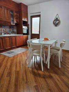 - une cuisine avec une table et des chaises blanches dans la chambre dans l'établissement Ilija Apartments, à Gevgelija
