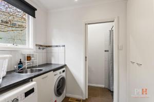 a kitchen with a sink and a washing machine at Spacious Retreat with Coastal Views in Cowes +31 photos