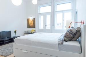 a white bedroom with a bed and a tv at NewSunny Apartment at the BudaCastle in Budapest