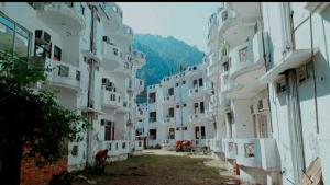 um grupo de edifícios brancos com uma montanha ao fundo em Vamoose Sachin International em Rudraprayāg