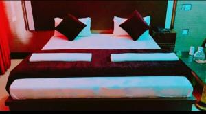 uma cama grande com lençóis e almofadas vermelhos e brancos em Vamoose Sachin International em Rudraprayāg