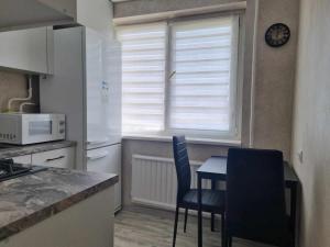 a kitchen with a table and chairs and a window at TILZES 24 APARTMENTS - self check in in Šiauliai