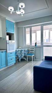 a living room with blue cabinets and a kitchen at Новая квартира с панорамным видом на горы in Almaty