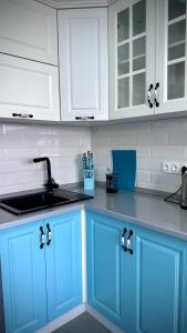 a kitchen with blue cabinets and a sink at Новая квартира с панорамным видом на горы in Almaty