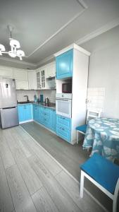 a kitchen with blue cabinets and a bed in it at Новая квартира с панорамным видом на горы in Almaty