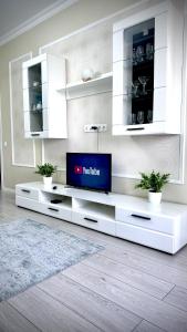 a living room with a tv on a white entertainment center at Новая квартира с панорамным видом на горы in Almaty