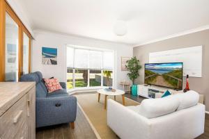 a living room with a couch and a tv at Salty Mermaid by Experience Jervis Bay in Vincentia