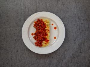 un plato blanco con pasta y salsa. en Via Ferrata Hotel, en Prousós