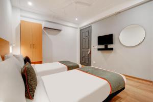 Habitación con 2 camas, espejo y TV. en Townhouse 219 en Gurgaon