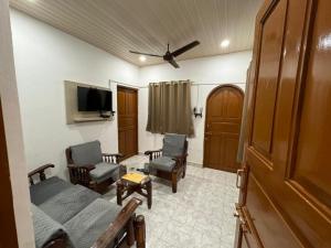 a room with a bed and chairs and a tv at Candolim beach touch flats in Candolim
