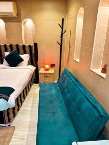 Omani House Inn نزل البيت العماني في نزوى‎: غرفة نوم مع أريكة زرقاء بجانب سرير