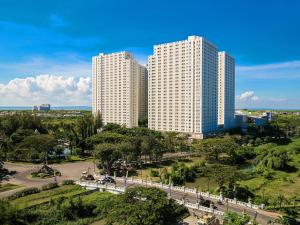 two tall white buildings in a city with a park at Modern 2BR Educity Apartment, Pakuwon City in Surabaya