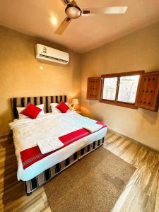 a bedroom with a large bed with red pillows at Omani House Inn نزل البيت العماني in Nizwa
