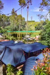 a group of blue tents with a bridge in the background at WULANDARI CAMPING GROUND in Bandung
