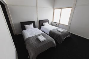 2 Einzelbetten in einem Zimmer mit 2 Fenstern in der Unterkunft UNPLAN Village Hakuba 2 in Otari