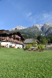 a building with a green lawn with mountains in the background at Brandstatthof Leogang in Leogang