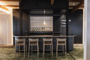 eine Bar mit vier Hockern in einem Zimmer in der Unterkunft UNPLAN Village Hakuba 2 in Otari
