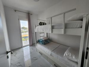 a white bedroom with bunk beds and a window at Anchor Apartments in Shëngjin