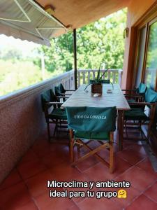 una mesa con sillas verdes en el porche en Eido da Consaca en Ponteareas
