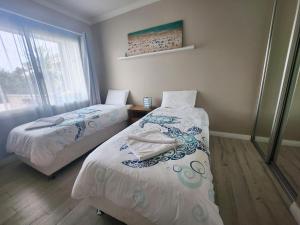 two beds in a small room with a window at Unit 34 Seafront Estate in Jurien Bay