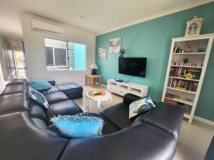 Unit 34 Seafront Estate في جوريين باي: غرفة معيشة مع أريكة جلدية وتلفزيون