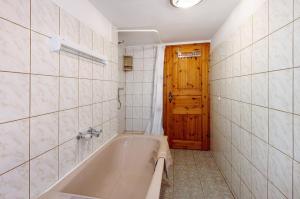 a bathroom with a tub and a wooden door at Ferienwohnung Gute Stube in Veckenstedt +17 photos