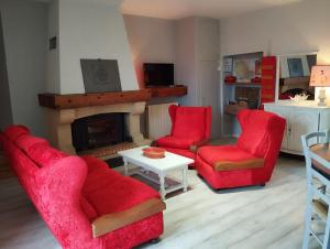 a living room with two red chairs and a fireplace at Gite Le Lucimond in Saint-André