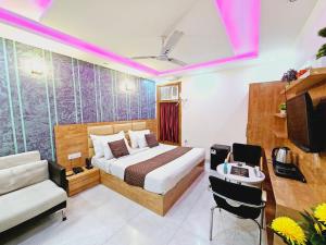 ニューデリーにあるHotel MARISA GRAND Near Delhi Airport BY Aero Homeのベッド、椅子、テレビが備わるホテルルームです。