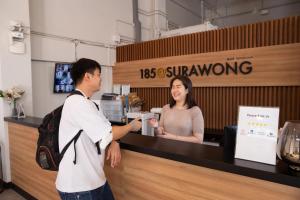 Un hombre y una mujer de pie en una caja registradora en 185@Surawong Residence, en Bangkok